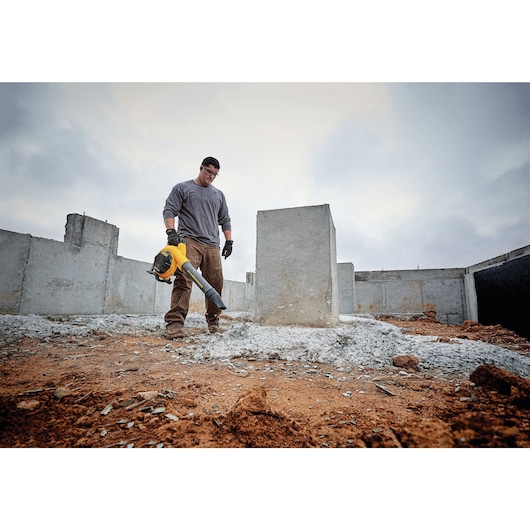 FLEXVOLT Handheld Blower being used by a worker to clear heavy jobsite debris on a rooftop