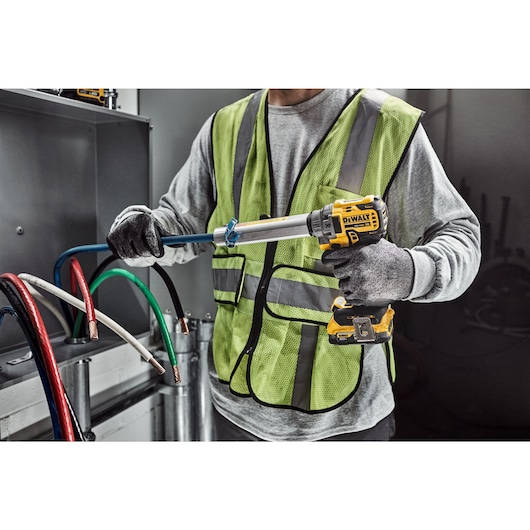 DEWALT Cable Stripper is used to strip a blue cable by a tradesman in an electrical room.