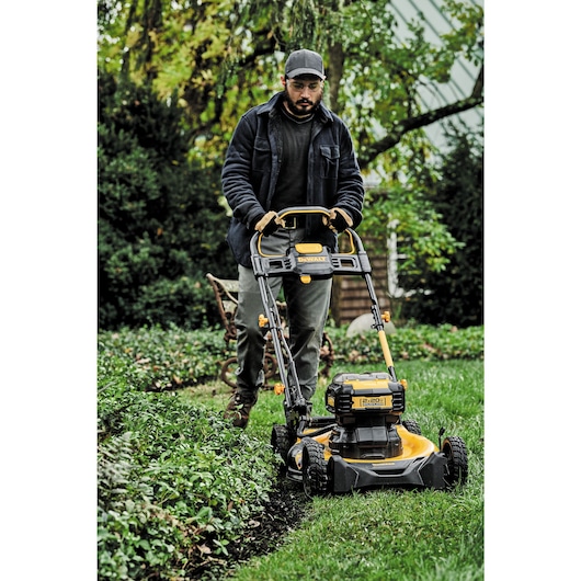 close up of brushless cordless push mower being used by a person to mow a lawn