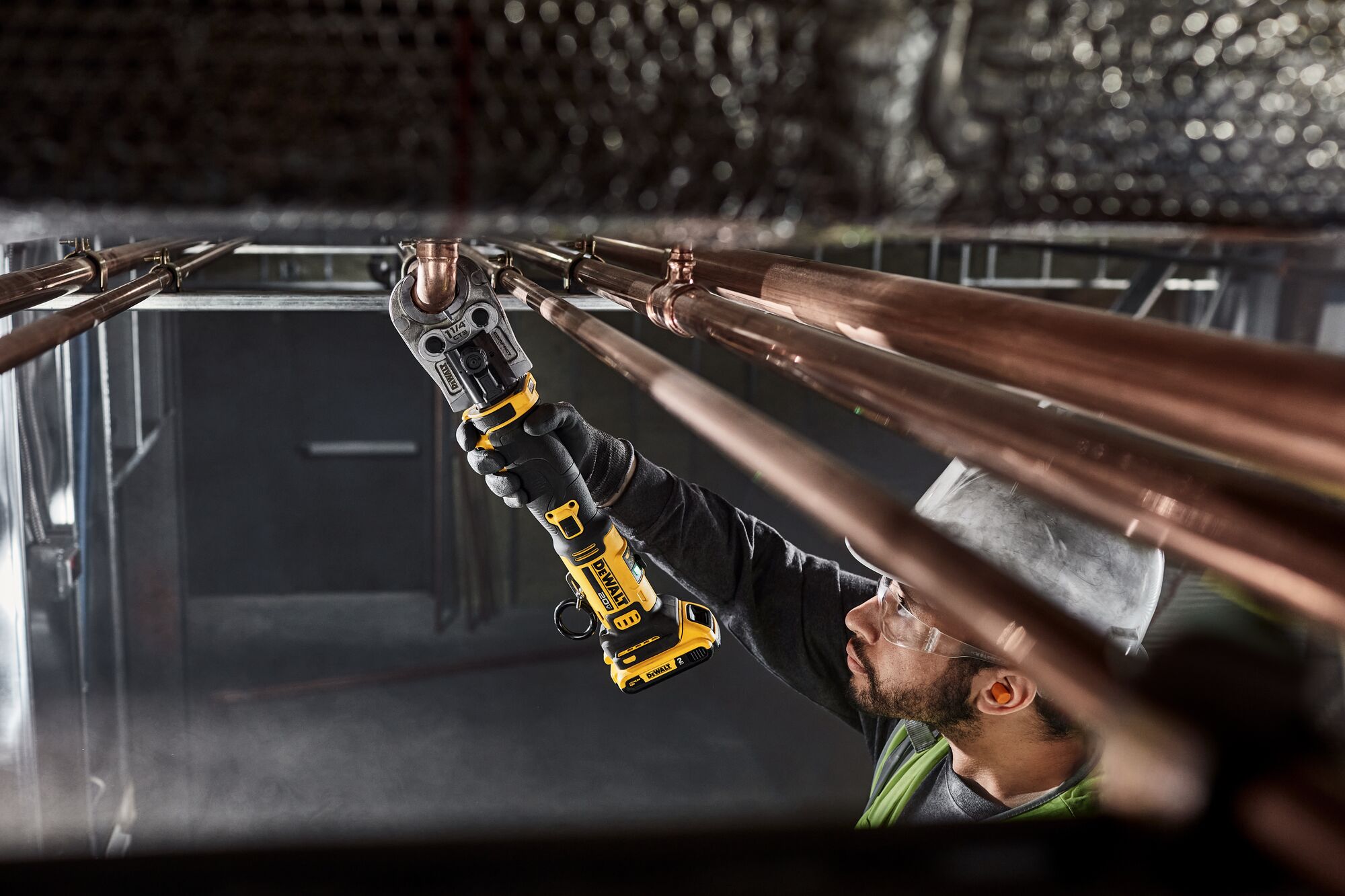 DEWALT Compact Press Tool pressing copper pipe overhead in a mechanical room. DEWALT Compact Press Tool pressing copper pipe overhead in a mechanical room.