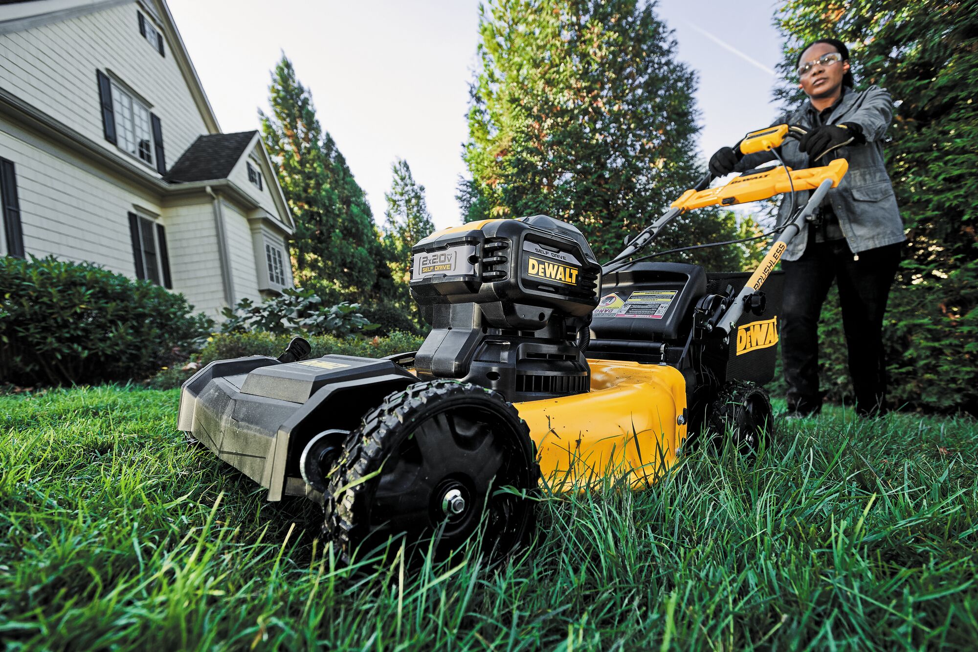 21 and a half inch Brushless Cordless Self Propelled mower in action by a person to trim grass in the front lawn of a house 21 and a half inch Brushless Cordless Self Propelled mower in action by a person to trim grass in the front lawn of a house