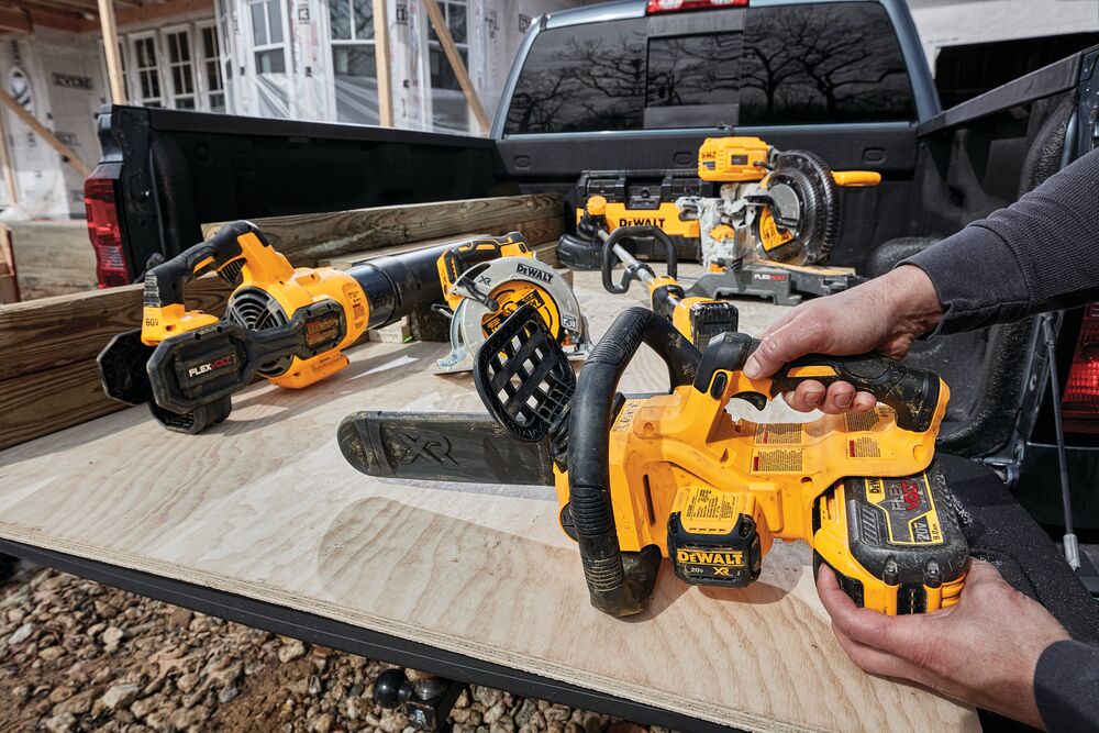 XR® Compact 12 inch Cordless Chainsaw sitting in cargo bed of a truck with or tools, being held by a person for battery insertion XR® Compact 12 inch Cordless Chainsaw sitting in cargo bed of a truck with or tools, being held by a person for battery insertion