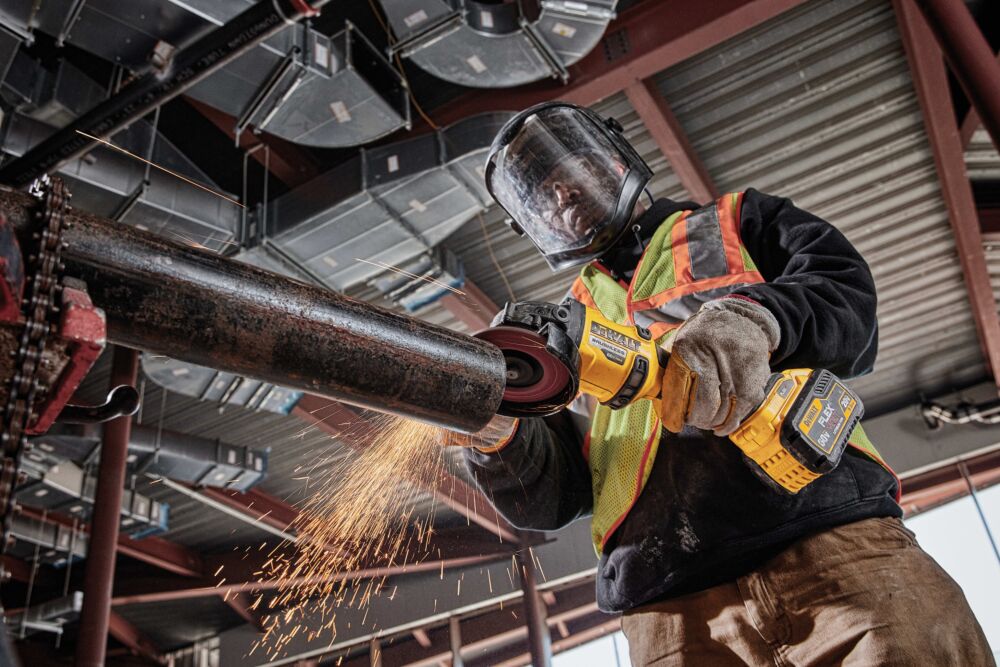 FLATHEAD PADDLE SWITCH SMALL ANGLE GRINDER WITH KICKBACK BRAKE being used by a person in a workshop FLATHEAD PADDLE SWITCH SMALL ANGLE GRINDER WITH KICKBACK BRAKE being used by a person in a workshop