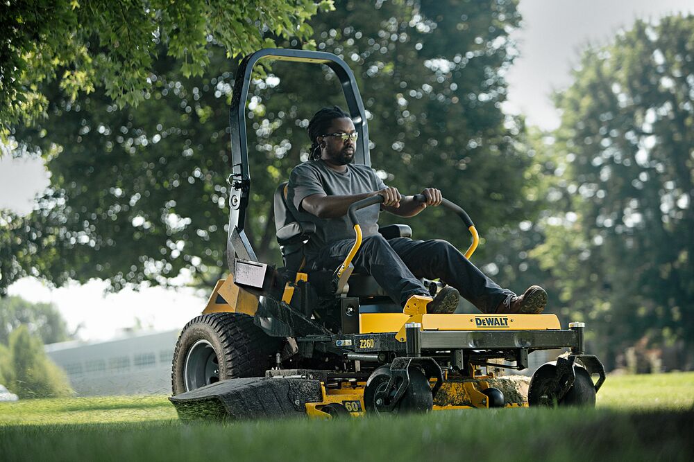 60 inch Kawasaki Gas Hydrostatic Commercial Zero Turn Mower being used by person to mow lawn outdoors. 60 inch Kawasaki Gas Hydrostatic Commercial Zero Turn Mower being used by person to mow lawn outdoors.