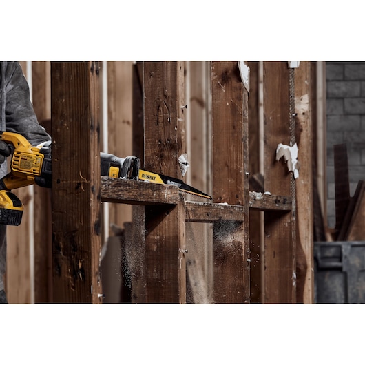 Person using ELITE SERIES Carbide Tipped Reciprocating Blade to cut wood frame