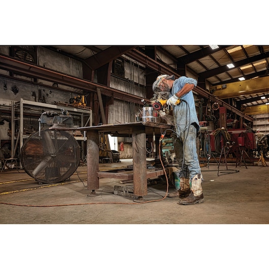 5 inch brushless paddle switch small angle grinder with kickback brake and nolock on grinding on a tall metal cylinder by a worker at a worksite.