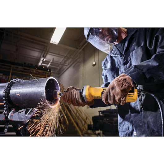 2 inch brushless variable speed paddle switch die grinder with nolock-on being used to grind on a metal pipe by a worker at a worksite.