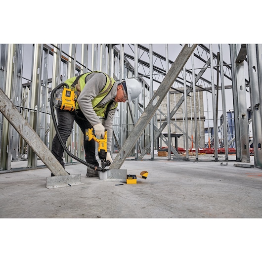 Dust extraction tube kit with hose being used by a person to cut out drywall.