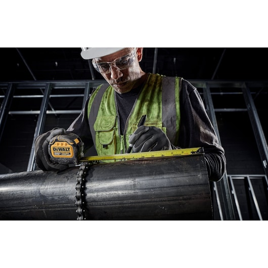Tough Series 25 feet Tape Measure being used by worker to measure metal pipe at worksite.