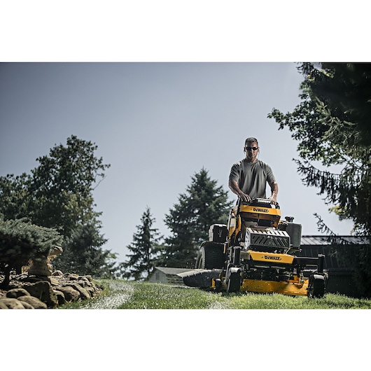 48 inch Kawasaki E F I Gas Hydrostatic Commercial Stand on Zero Turn Mower being used by person to mow lawn.
